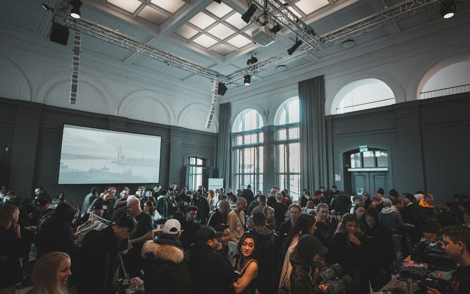 An audience in a grand hall listening to a speaker